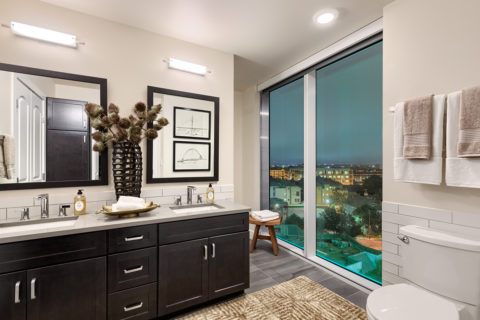 Luxurious bathrooms with large windows, dark cabinetry and framed mirrors